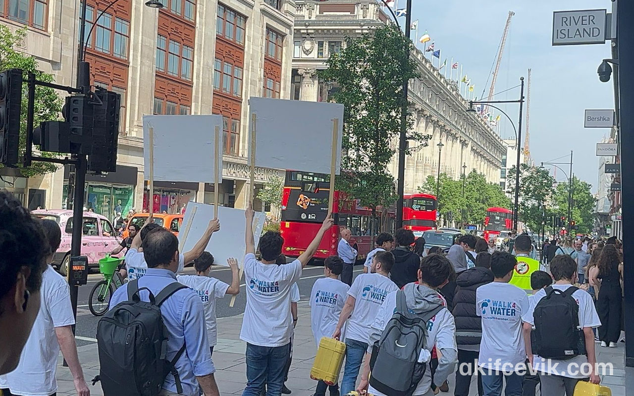 londra sokaklarında su bidonlarıyla yürüyen grup